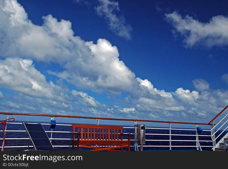 View of a Cruise Ship Railing, Stairs and Bench with beautiful Tropical Sky in the background