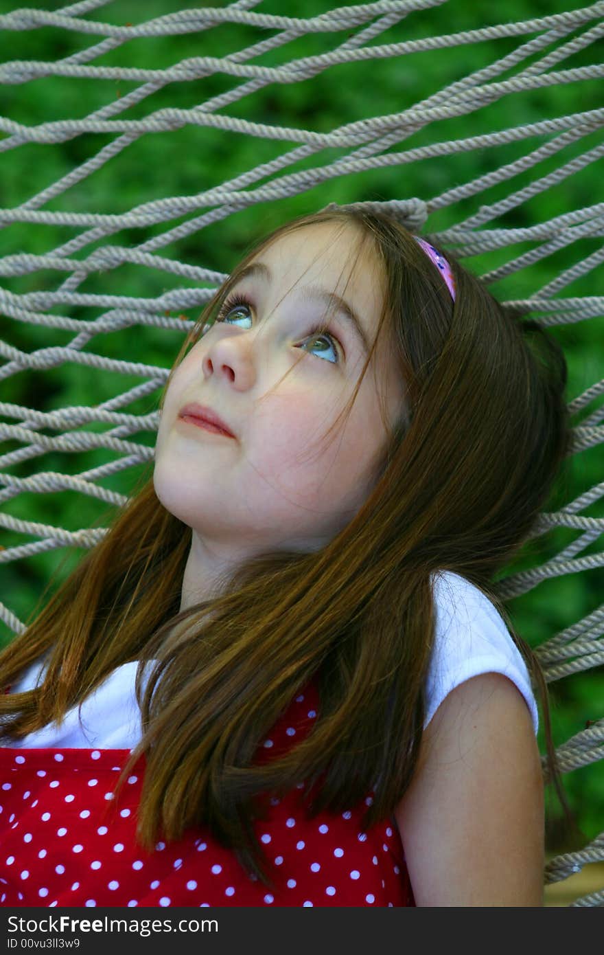 Eight year old child daydreaming in a hammock