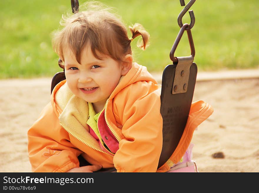 Little girl smiling and swinging on park playground. Spring time. Little girl smiling and swinging on park playground. Spring time.