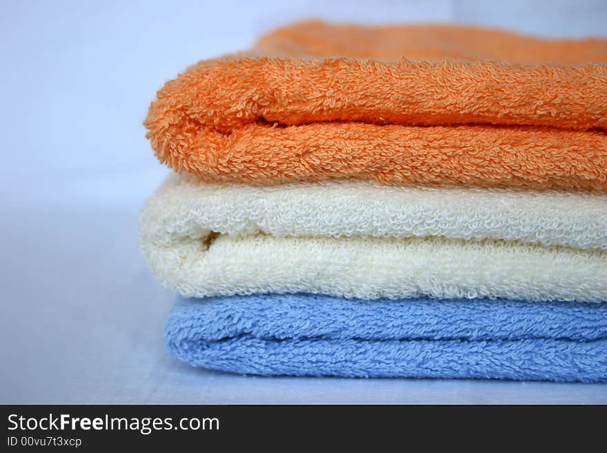 Three coloured towels: orange, white, blue