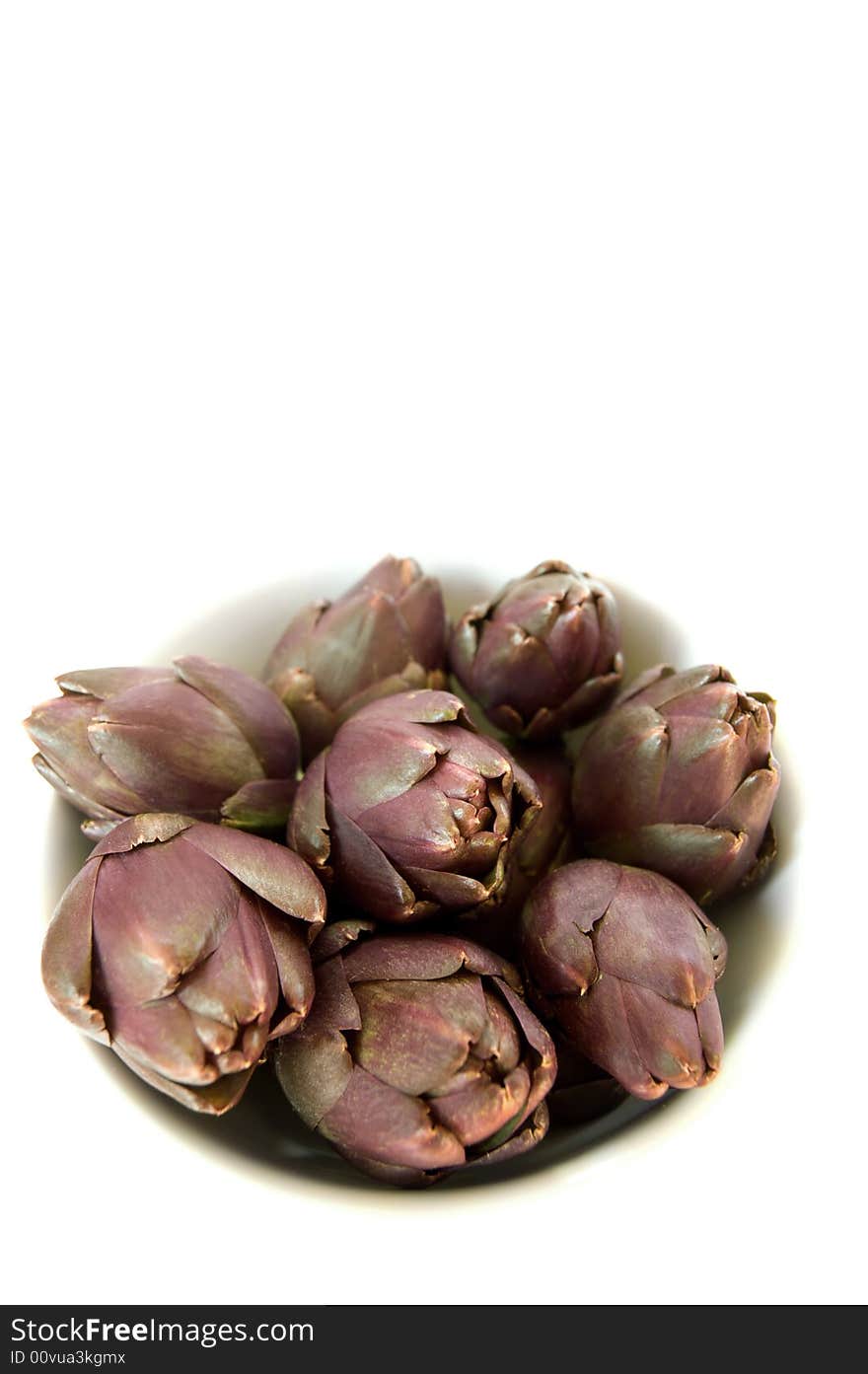 Purple artichokes in a bowl, isolated on white background