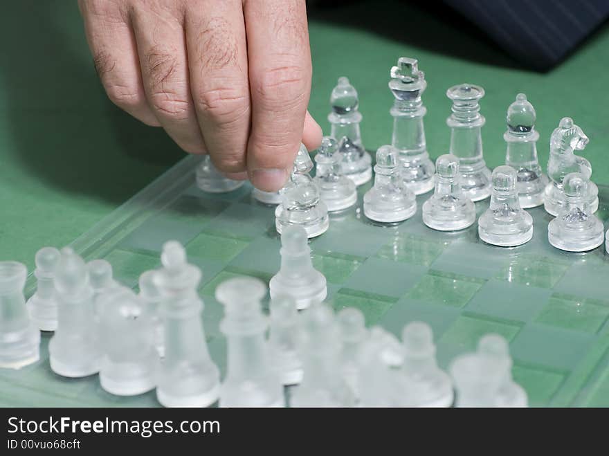 A businessman in a suit, sitting on the floor cross-legged, moving a chess piece. A businessman in a suit, sitting on the floor cross-legged, moving a chess piece.