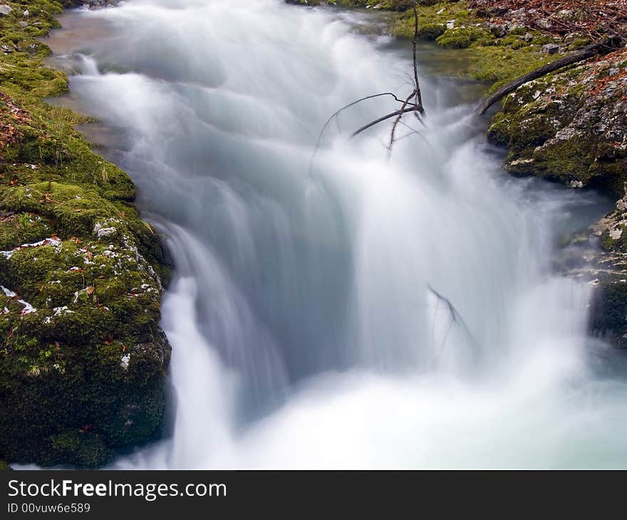 Mountain stream flowing over rocky ground making cascades.