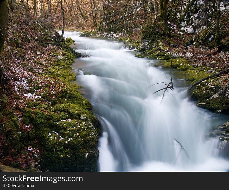 Mountain stream flowing over rocky ground making cascades.