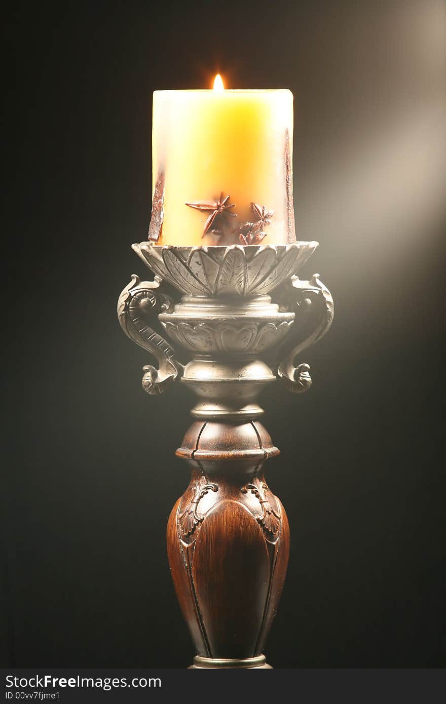 Antique wooden candlestick with ray of light isolated on black background