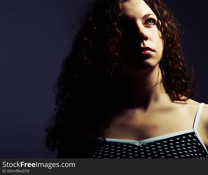 A low-key portrait about a pretty lady with white skin and long brown wavy hair whose look is enchanting and she wears a nice black dress with white dots. A low-key portrait about a pretty lady with white skin and long brown wavy hair whose look is enchanting and she wears a nice black dress with white dots