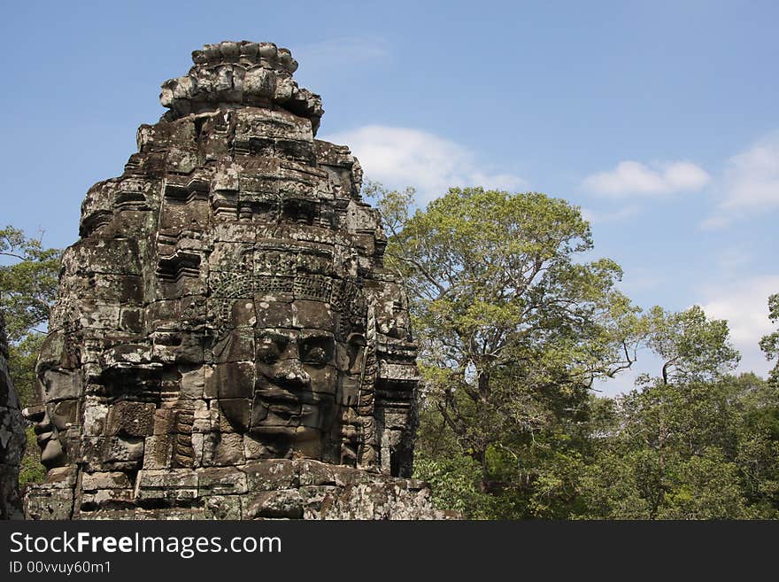 UNESCO heritage site Angkoro Temples in Cambodia. Bayon temple. face of idol with the trolpical jungle as background. UNESCO heritage site Angkoro Temples in Cambodia. Bayon temple. face of idol with the trolpical jungle as background