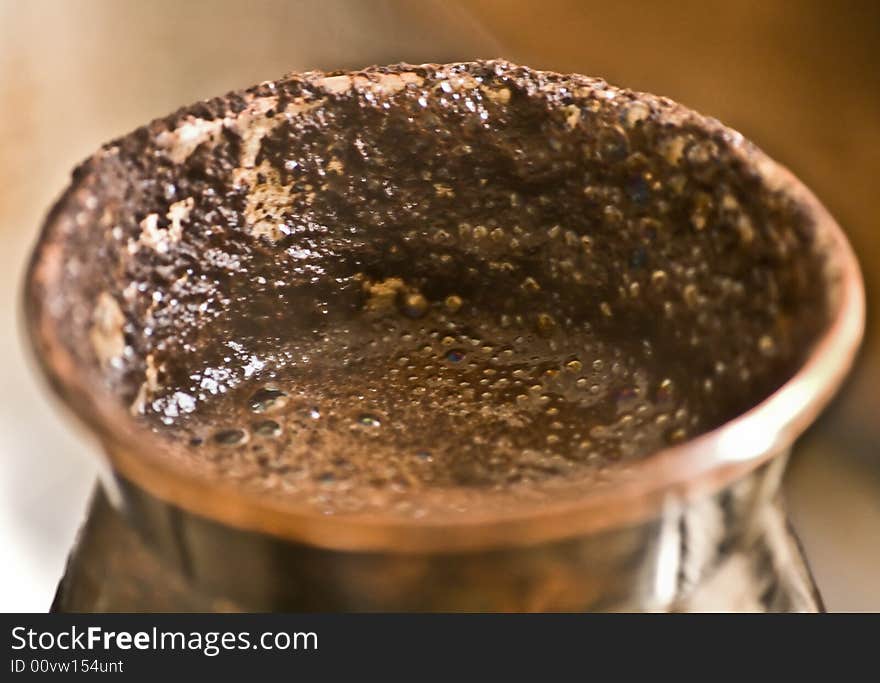 Close-up of copper cezve with boiled over black coffee. Close-up of copper cezve with boiled over black coffee