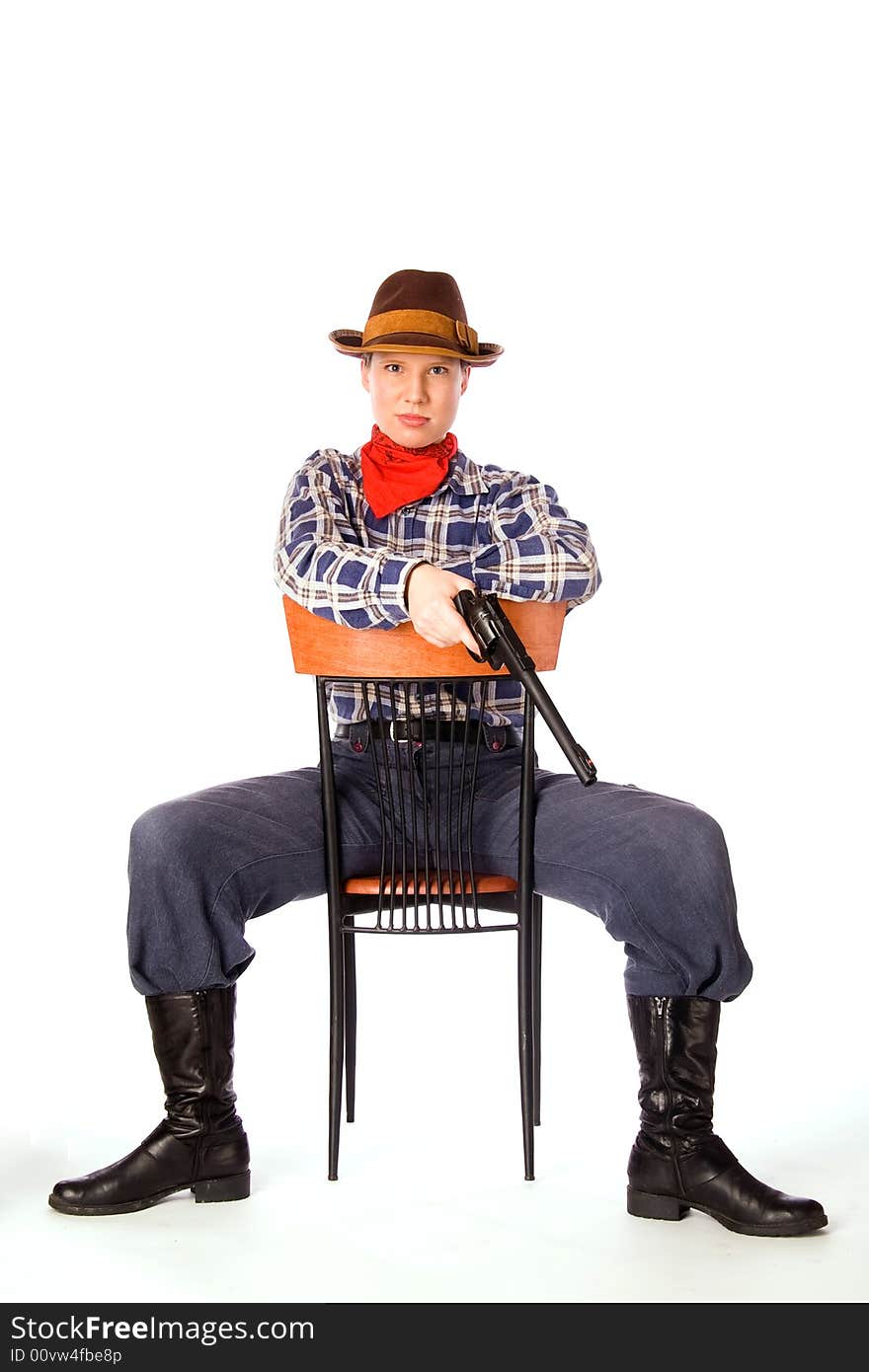 Resolute cowgirl with gun sitting on the chair (isolated on white)