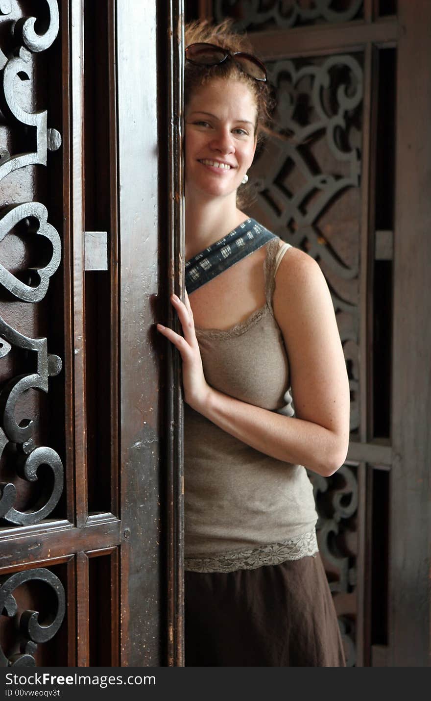 Happy woman leaning on a carved wooden door.