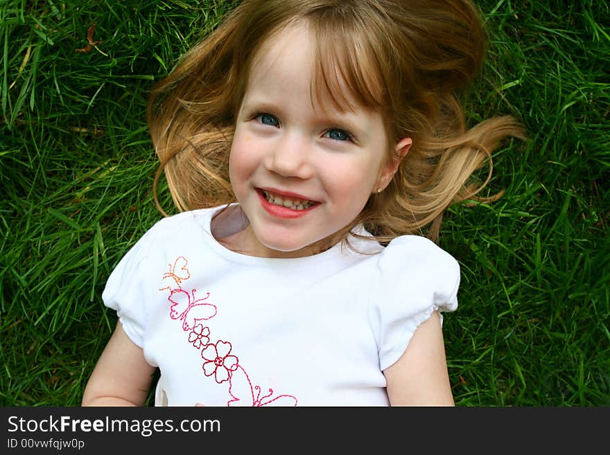 A beatiful four year old girl laying in the grass. A beatiful four year old girl laying in the grass