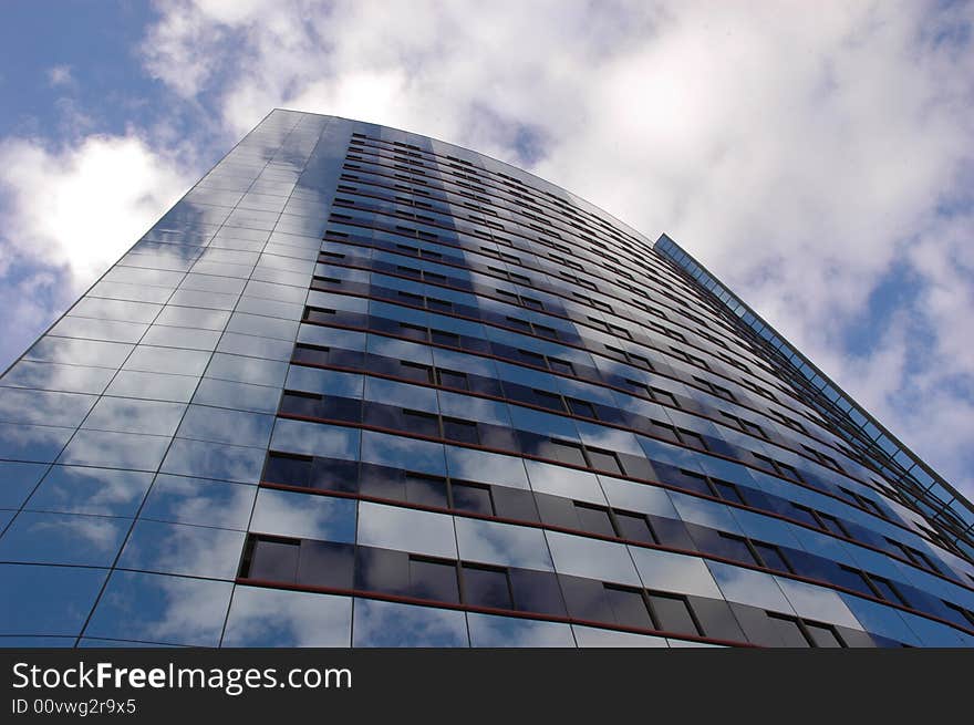 The reflection of the sky and clouds on a curved building. The reflection of the sky and clouds on a curved building.