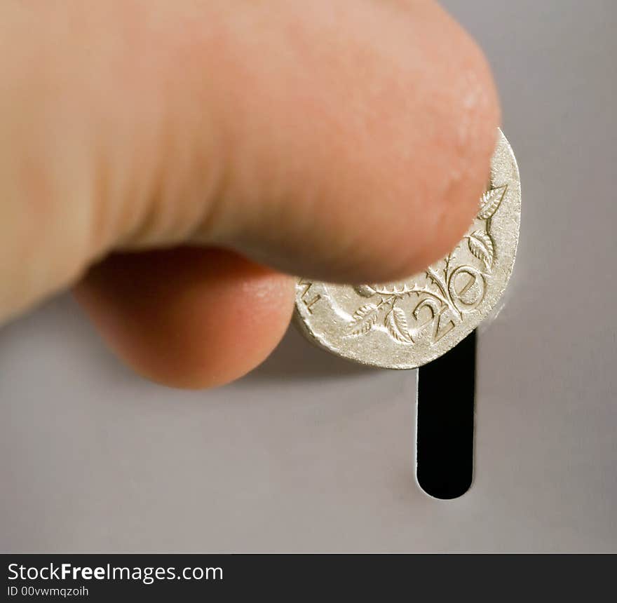 Photo of someone placing twenty pence into a savings tin. Photo of someone placing twenty pence into a savings tin