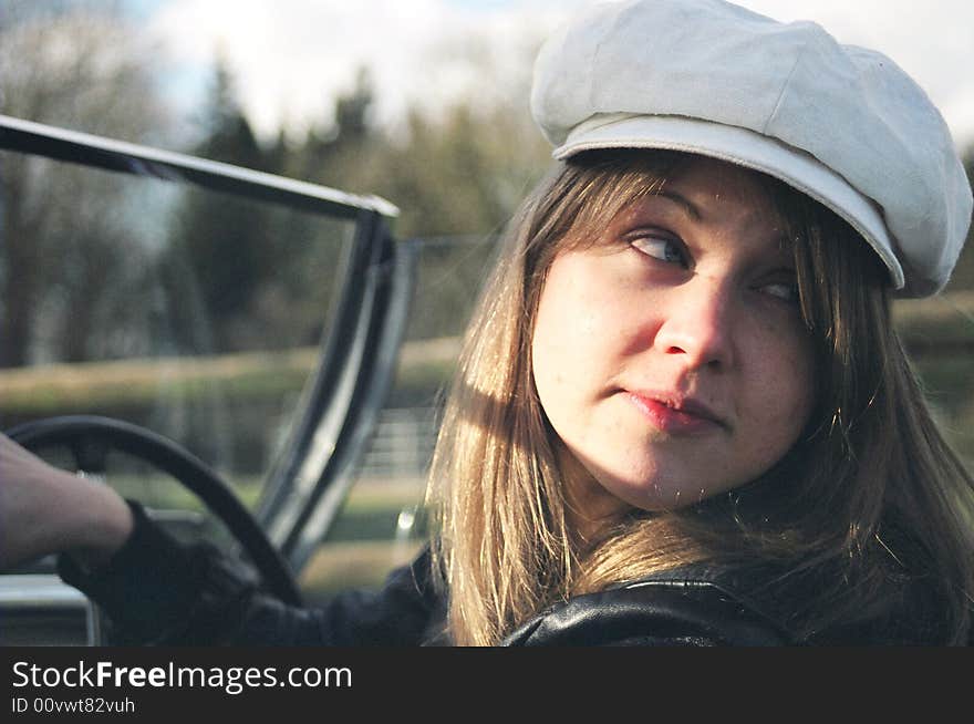 A Sixties looking girl in a car looksback over her shoulder. A Sixties looking girl in a car looksback over her shoulder