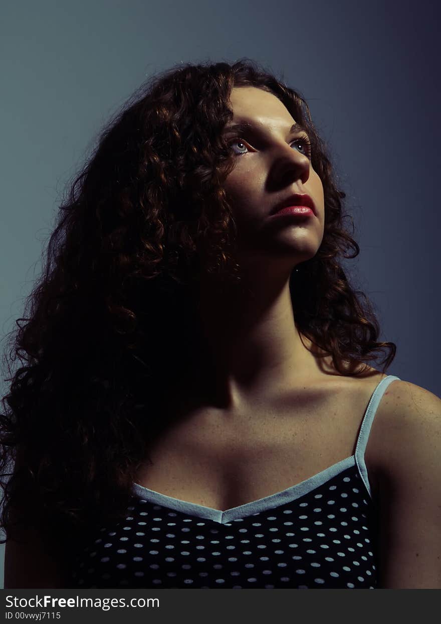 A low-key portrait about a pretty lady with white skin and long brown wavy hair who wears a nice black dress with white dots and she is looking up and desires. A low-key portrait about a pretty lady with white skin and long brown wavy hair who wears a nice black dress with white dots and she is looking up and desires