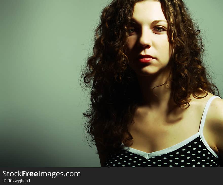 A low-key portrait about a pretty lady with white skin and long brown wavy hair whose look is attractive and she wears a nice black dress with white dots. A low-key portrait about a pretty lady with white skin and long brown wavy hair whose look is attractive and she wears a nice black dress with white dots