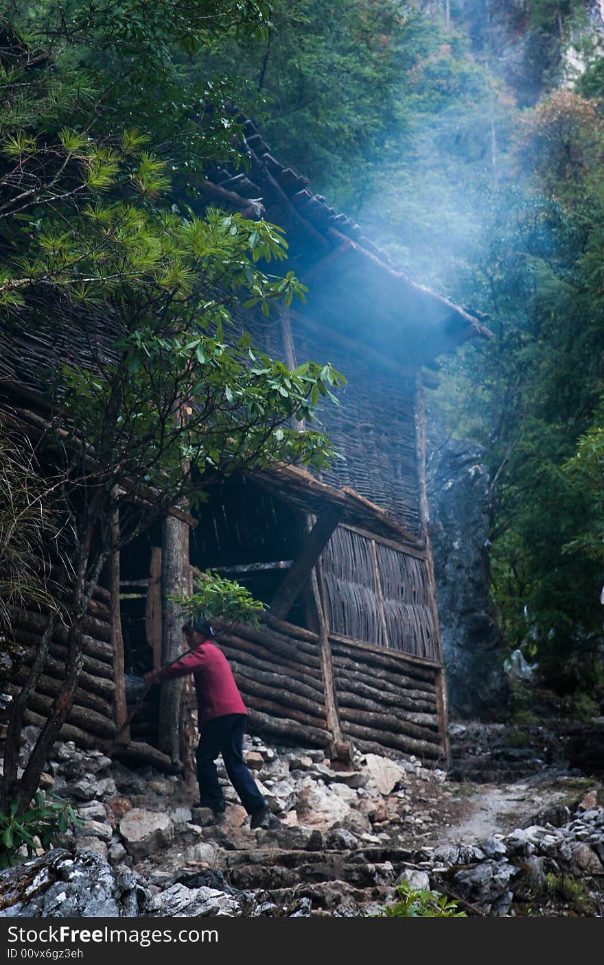 A wooden house on the hill,with smoke came out from the kitchen,the woman was going in.the hill is a very nice and quiet place with a stream and waterfall.only this house on the hill.