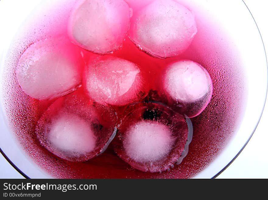 Wine-glass with a red drink and an ice