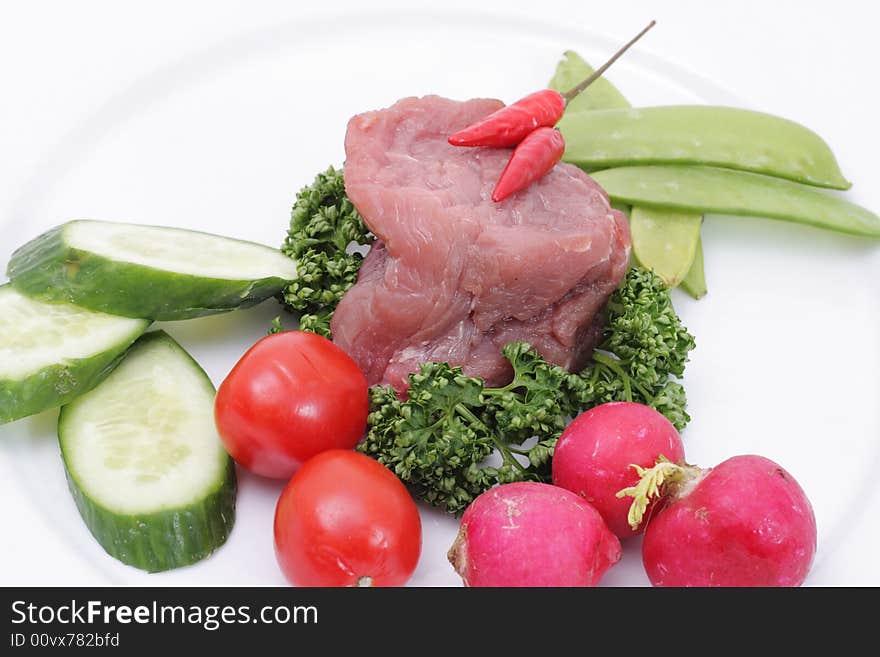 Vegetables and raw meat on a plate. Isolated on a white background