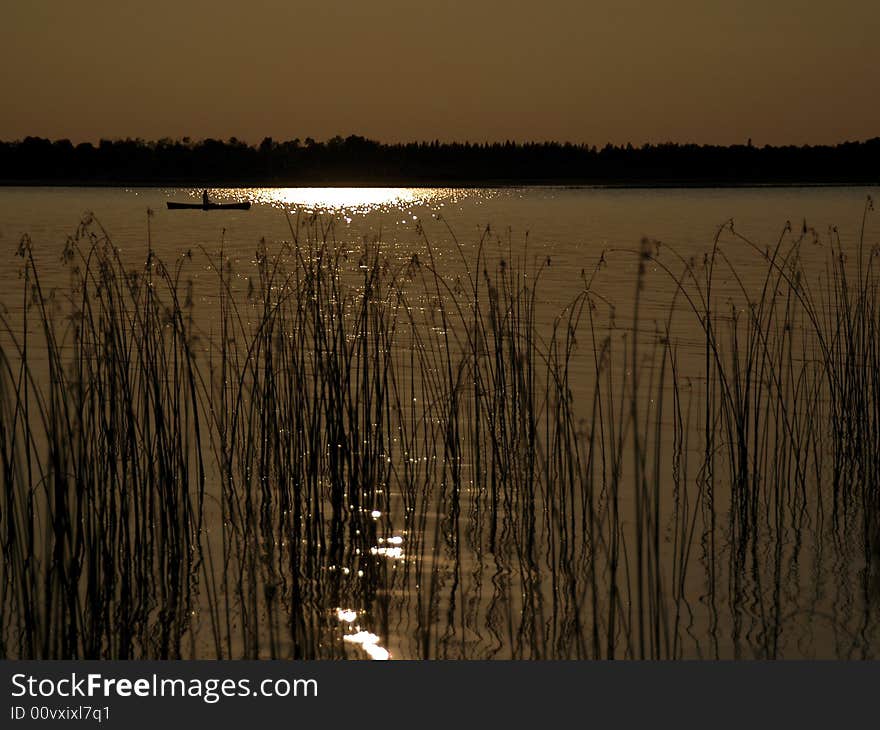 Silhouette canoe paddling across lake. Silhouette canoe paddling across lake