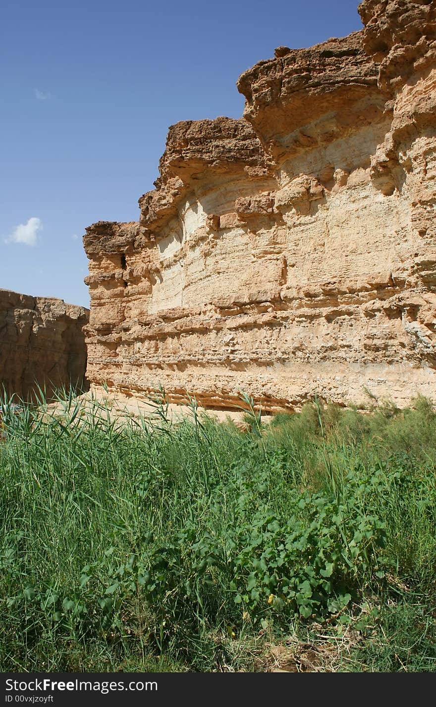 Desert rock, blue sky, green grass