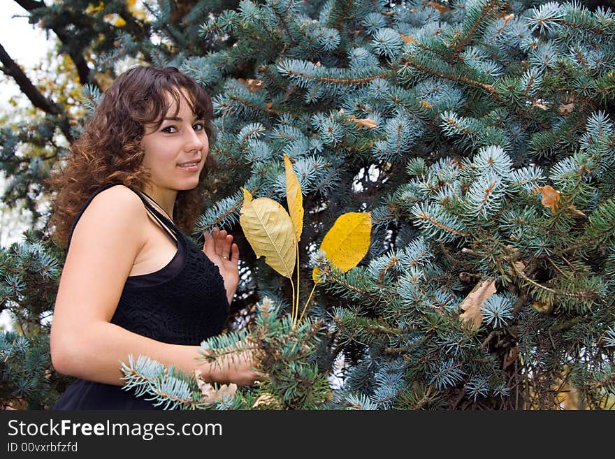 Young beautiful woman standing near spruce tree and smiling