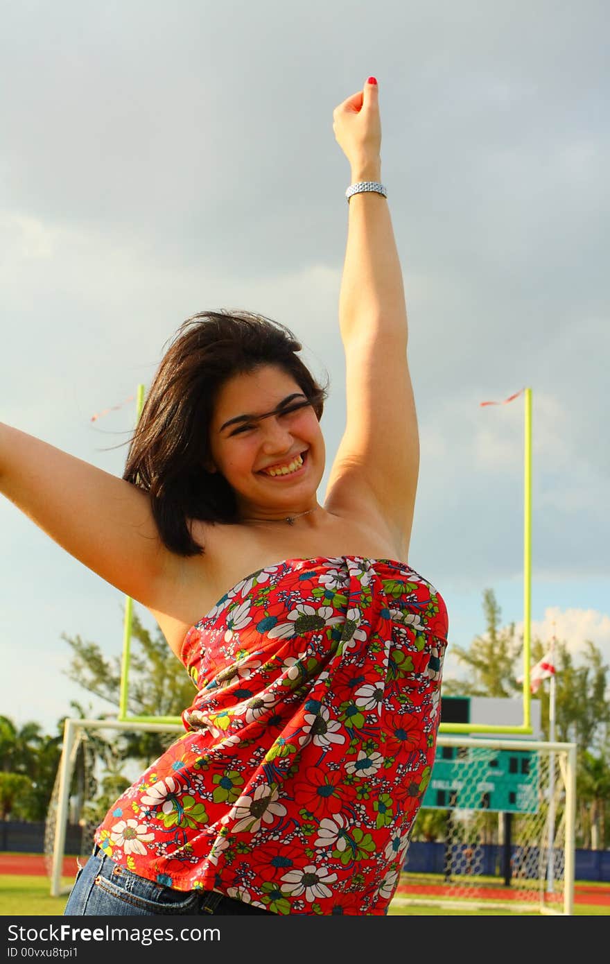 Pretty young woman modeling on a sports field with storm clouds in the background. Pretty young woman modeling on a sports field with storm clouds in the background.