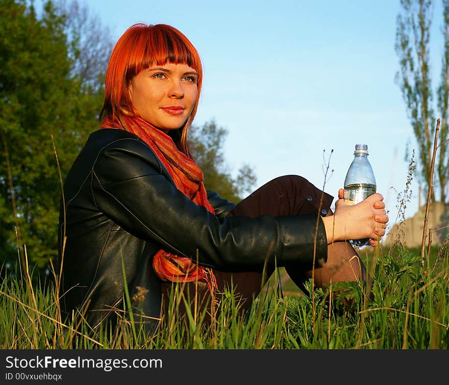 Young girl drinks water on a background of the sky