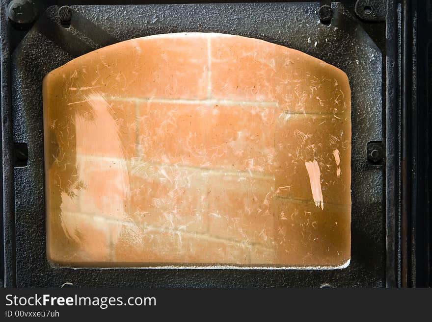 Fire box door. Stove glass with soot and various traces.