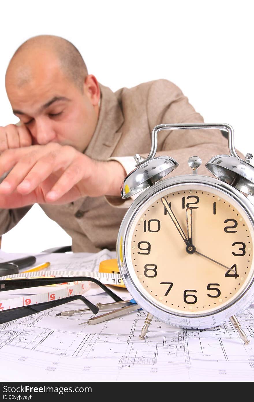 A businessman sleepy with architectural plans at desk