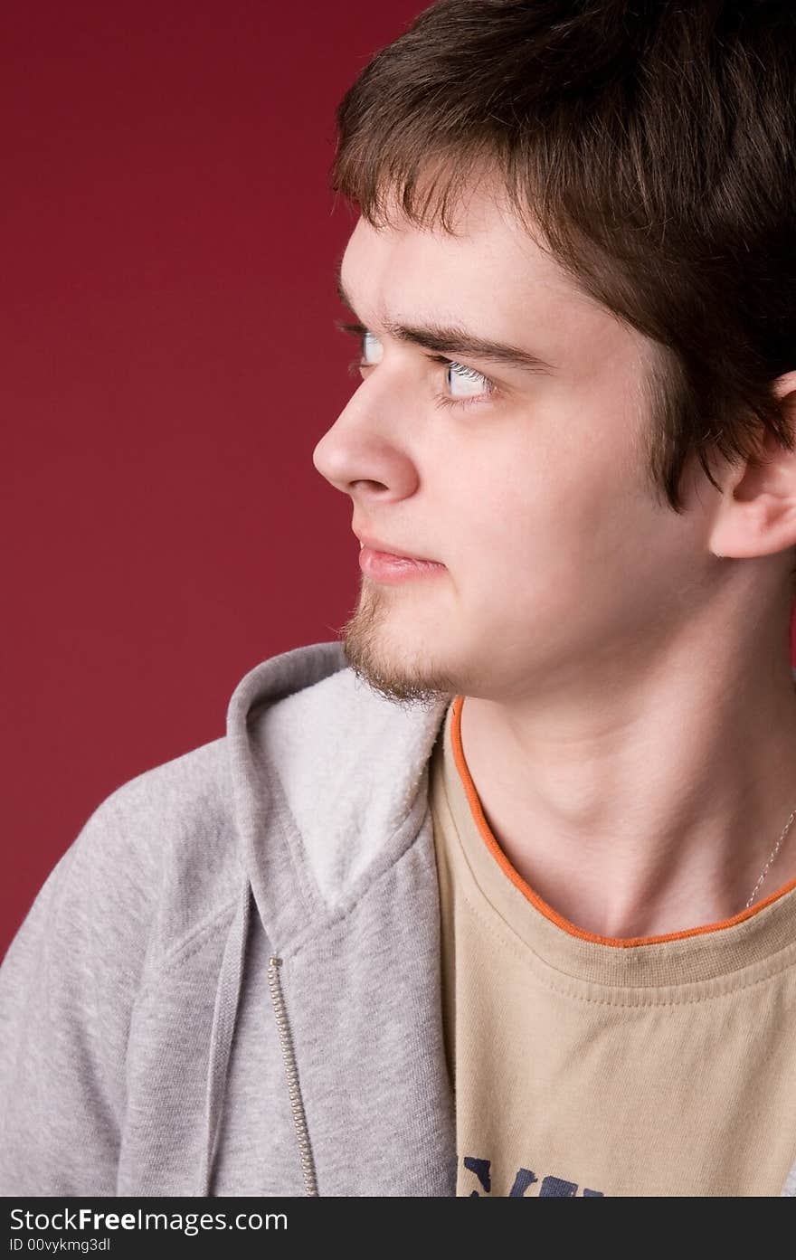 The young guy in studio on a red background