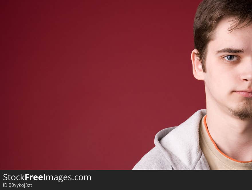 The young guy in studio on a red background