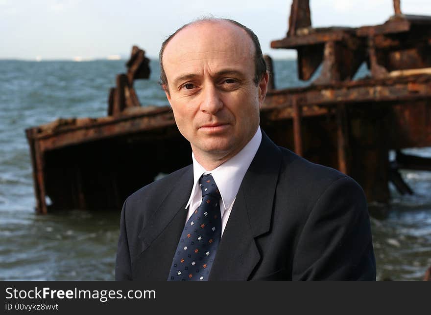 Businessman on the beach by an old wreck, dressed in business attire in front of a very old rusting shipwreck on the beach, with his briefcase and walking past rusting shipwreck thinking is this where my business will end up. Businessman on the beach by an old wreck, dressed in business attire in front of a very old rusting shipwreck on the beach, with his briefcase and walking past rusting shipwreck thinking is this where my business will end up