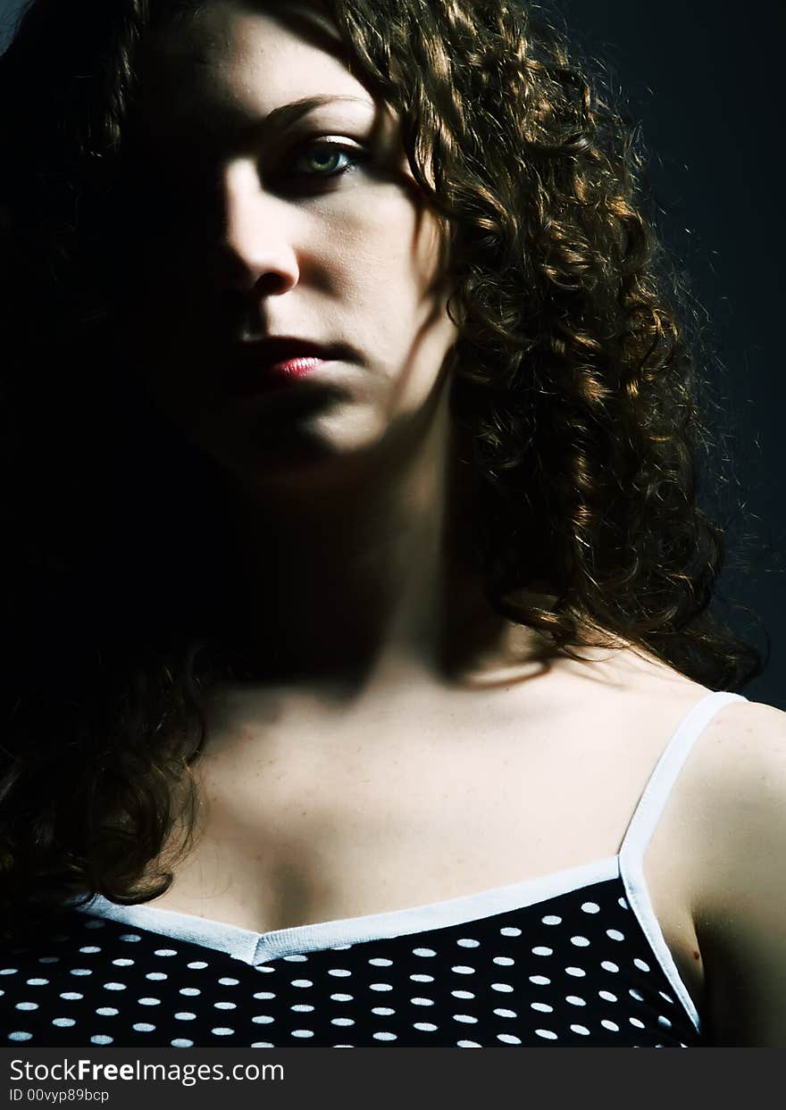 A low-key portrait about a pretty lady with white skin and long brown wavy hair whose look is enchanting and she wears a nice black dress with white dots. A low-key portrait about a pretty lady with white skin and long brown wavy hair whose look is enchanting and she wears a nice black dress with white dots