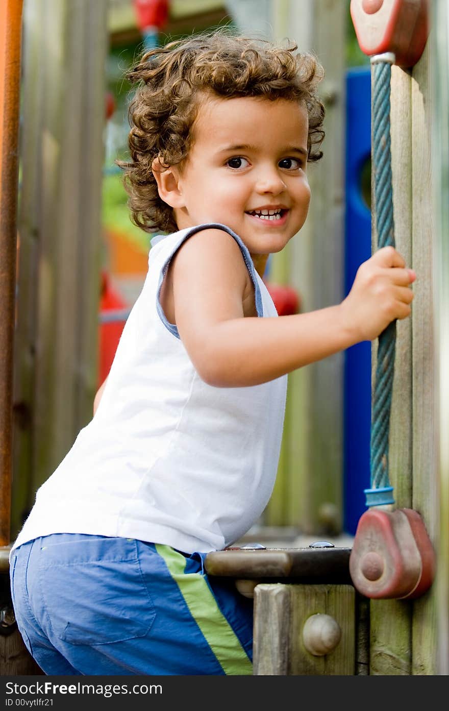 A cute young kid playing on a climbing frame in a park. A cute young kid playing on a climbing frame in a park