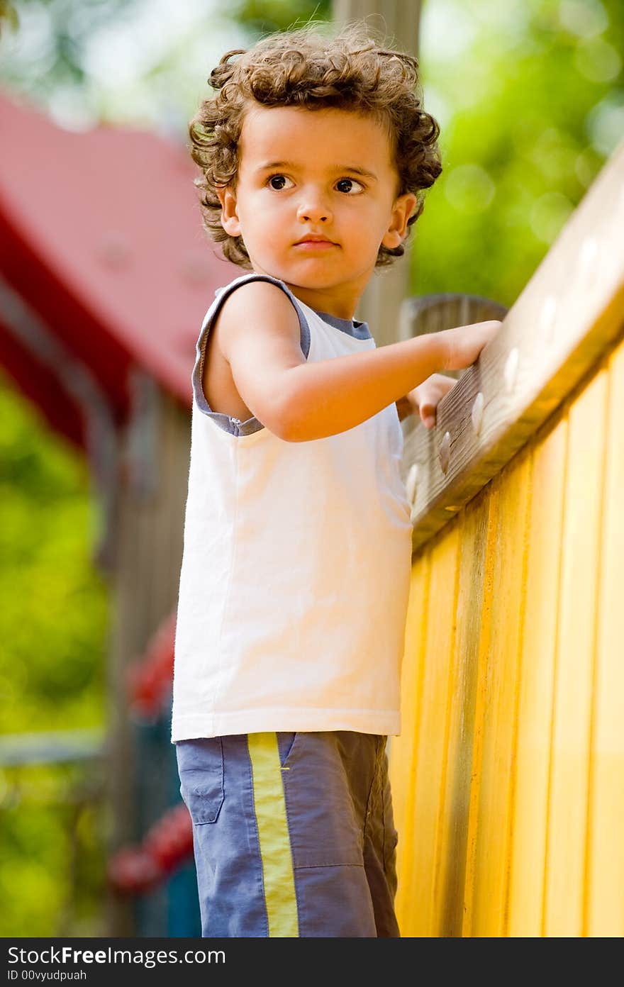 A cute young kid playing on a climbing frame in a park. A cute young kid playing on a climbing frame in a park