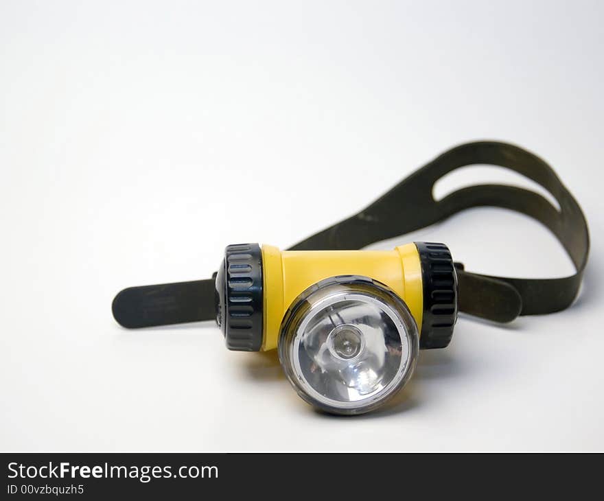 A yellow flashlight headlamp on a white background. A yellow flashlight headlamp on a white background.