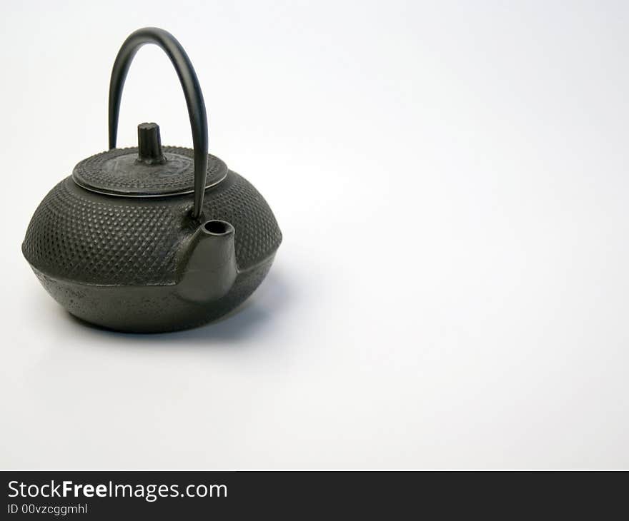 A small cast iron teapot on a white background. A small cast iron teapot on a white background.