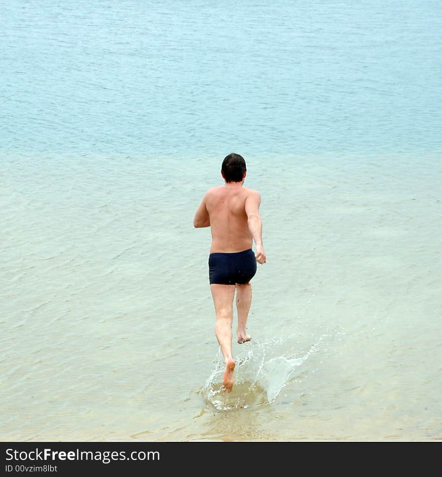 Young sportive man is rinning to water to dive in. Young sportive man is rinning to water to dive in.