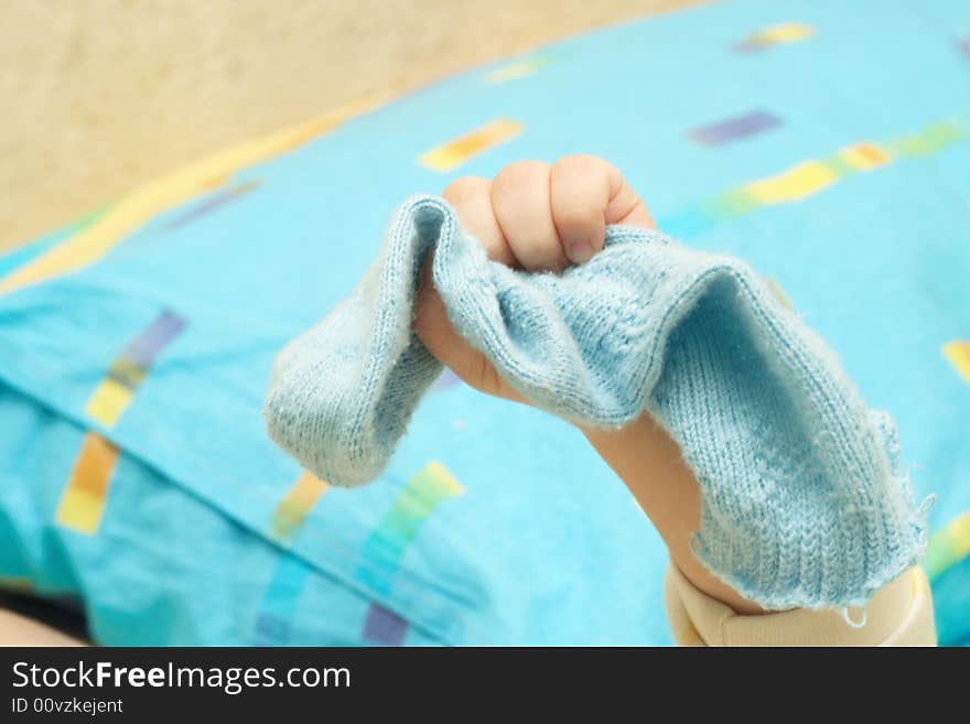 The hand of the child compresses a blue sock. The hand of the child compresses a blue sock