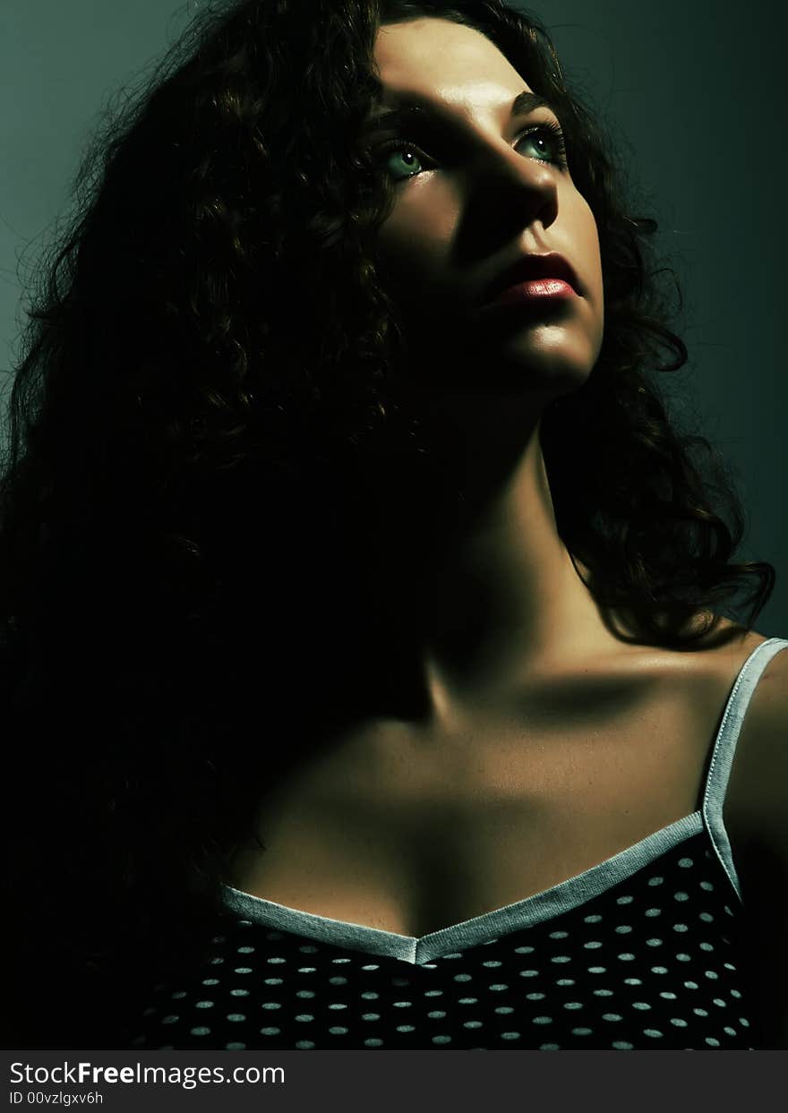 A low-key portrait about a pretty lady with white skin and long brown wavy hair who wears a nice black dress with white dots and she is looking up and desires something. A low-key portrait about a pretty lady with white skin and long brown wavy hair who wears a nice black dress with white dots and she is looking up and desires something