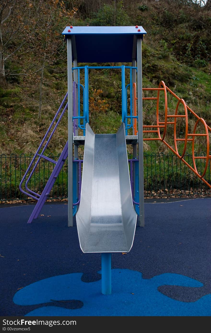 Photo of a childrens playground slide with a safety mat covering the ground