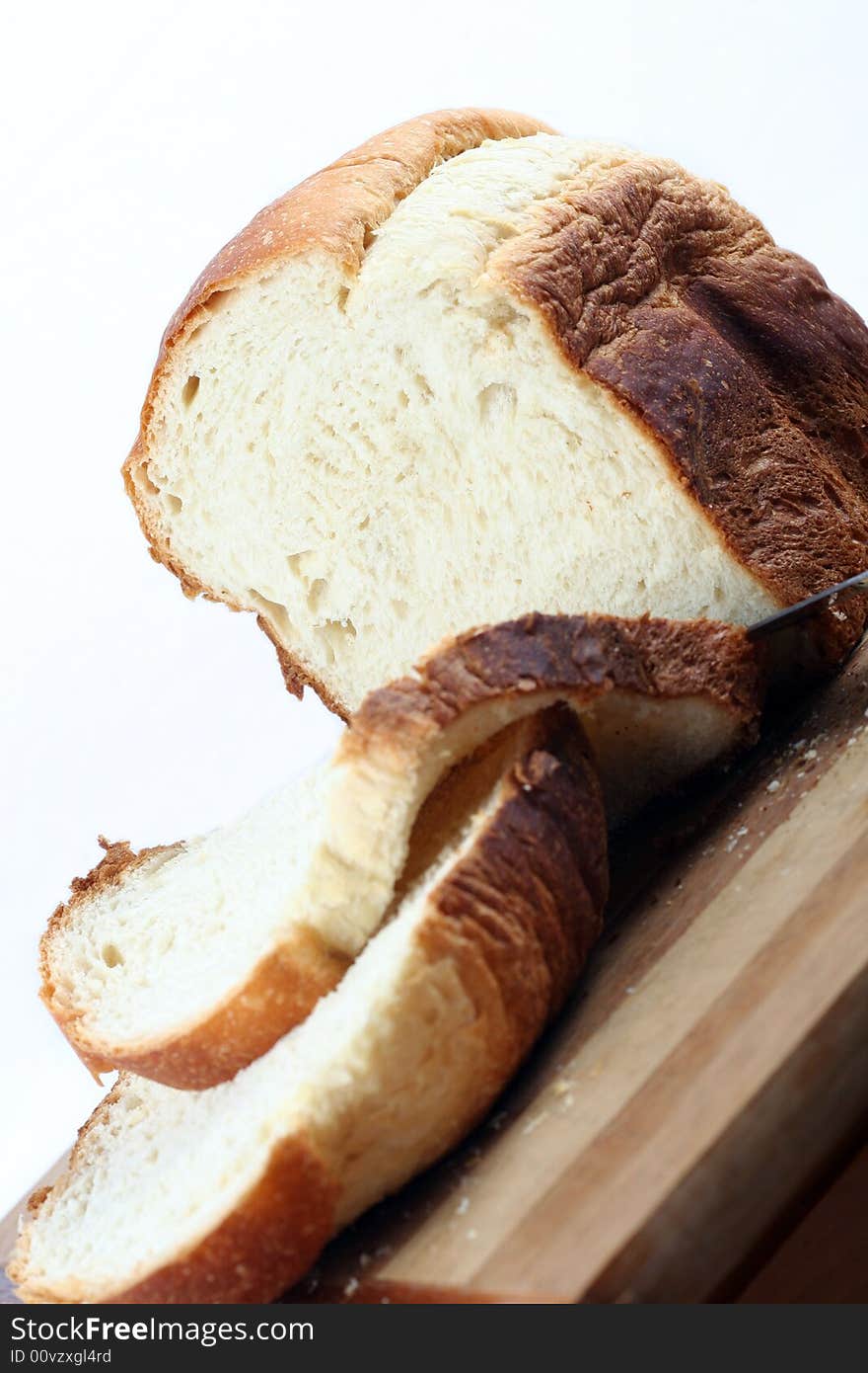 A loaf of home made bread that is partially sliced. A loaf of home made bread that is partially sliced.