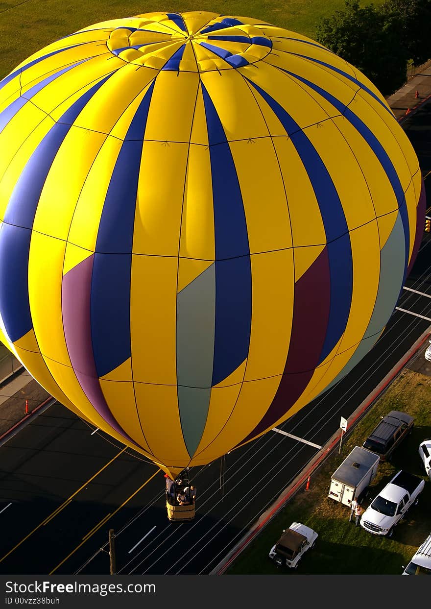 Yellow hot air balloon flying over road viewed from above. Yellow hot air balloon flying over road viewed from above