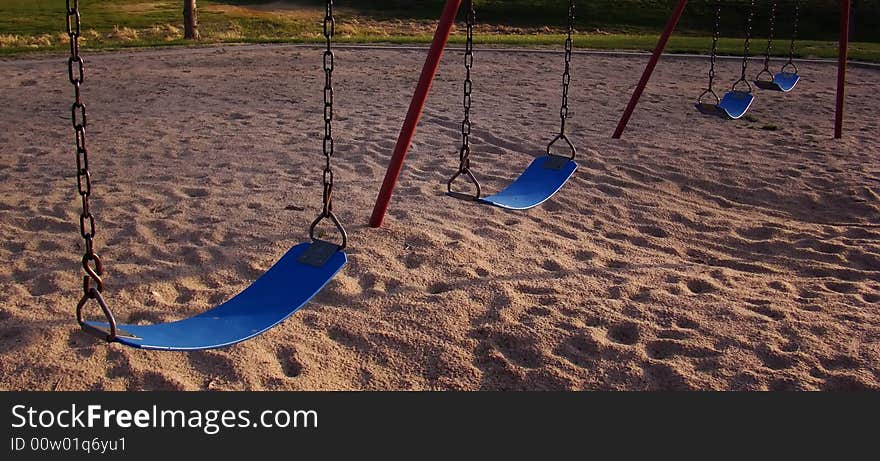 Blue seats of swing set on playground in small Midwestern city park. Blue seats of swing set on playground in small Midwestern city park