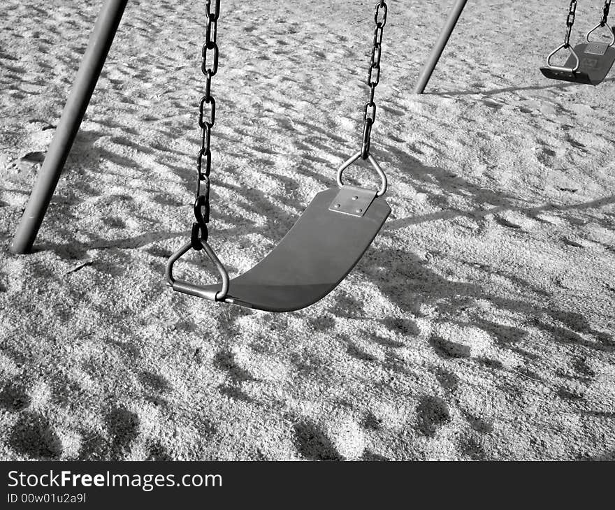 Black/white image of swing seats on playground in a park