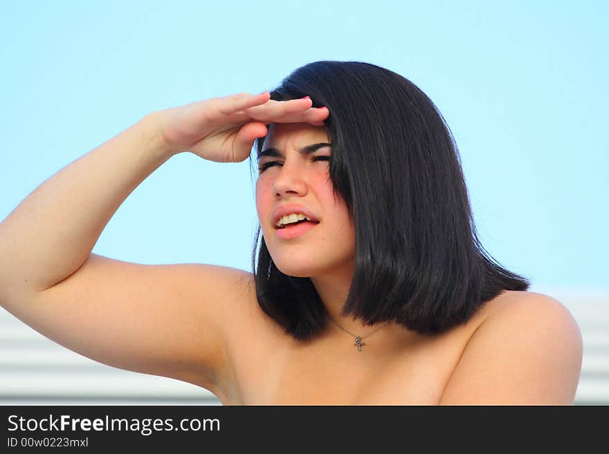 Woman looking at something in the distance with her hand by her head.