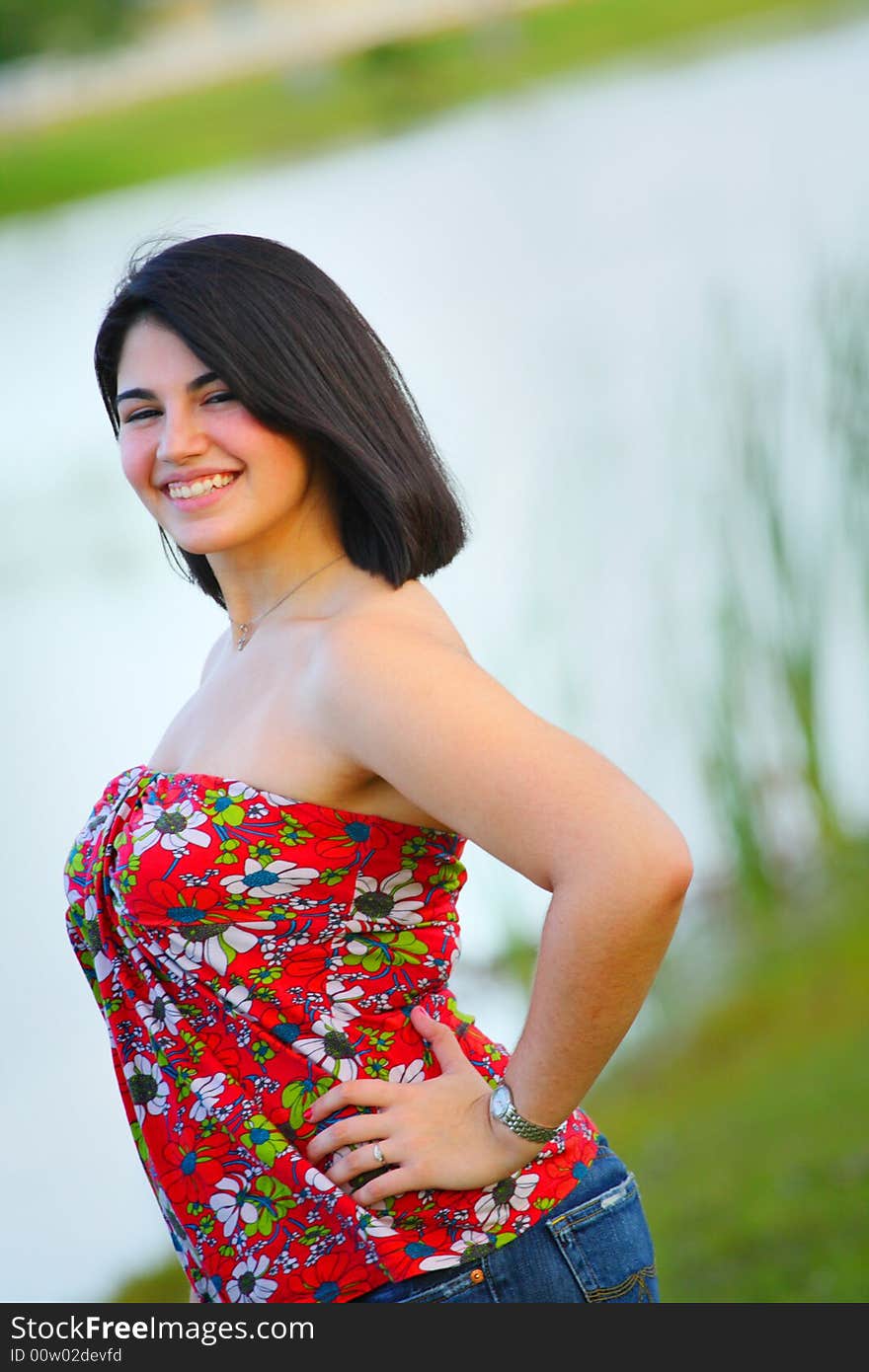 Woman standing by a pond smiling. Woman standing by a pond smiling