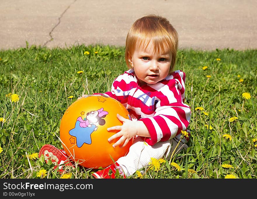 The little girl with ball on a grass