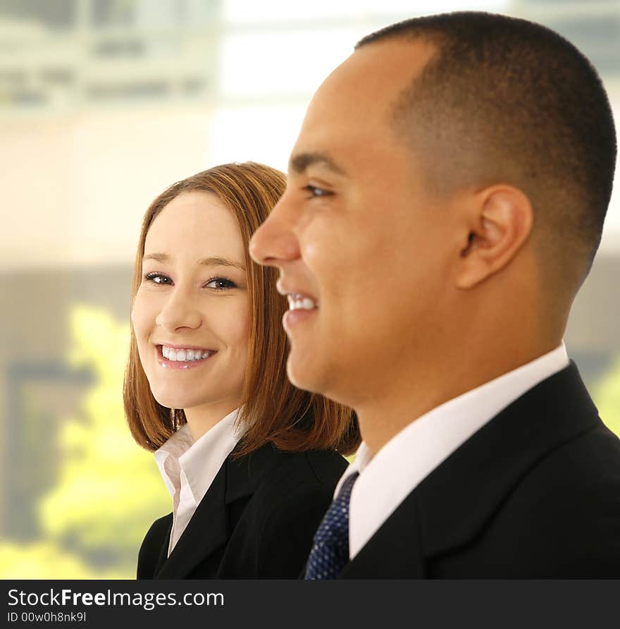 Shot of two business people standing side by side. the woman look to the camera and smile while the man look to the side. Shot of two business people standing side by side. the woman look to the camera and smile while the man look to the side